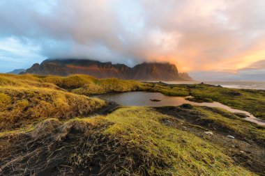 Büyülü manzara Vestrahorn dağlar ve gündoğumu, İzlanda'daki siyah kum tepeleri. Panoramik manzaralı bir Colorfulseascape Stokksnes burun.