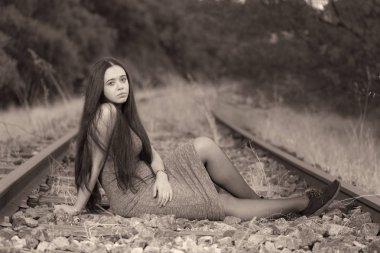Tren yolu üzerinde oturan genç kadın