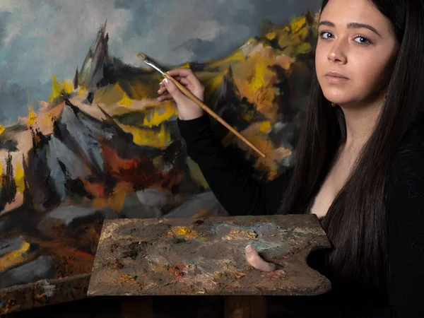 Young woman painting a canvas on an easel.