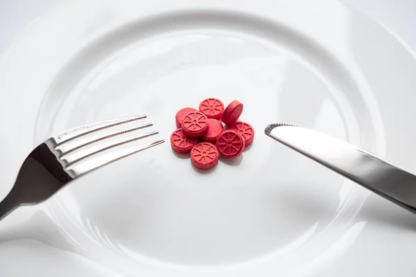 Beyaz tabak çatal ve bıçak hapları. Yemek yerine hap. Diyet.