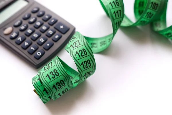 Hesap makinesi ve beyaz zemin üzerine şerit metre