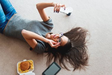 Halı üzerinde bir cep telefonu kullanan güzel genç kadın