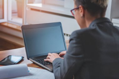 ofiste bir dizüstü bilgisayar üzerinde çalışan genç iş kadını 