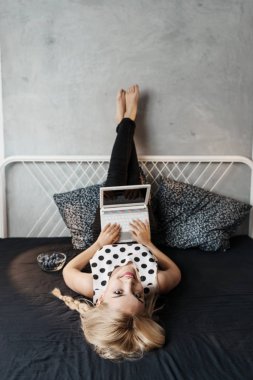 Bir dizüstü bilgisayar kullanarak ve gülümseyen genç kadın