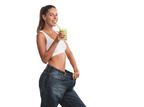 年轻的女人在特大的裤子持有健康 绿色的冰沙 孤立的白色背景 — 图库照片