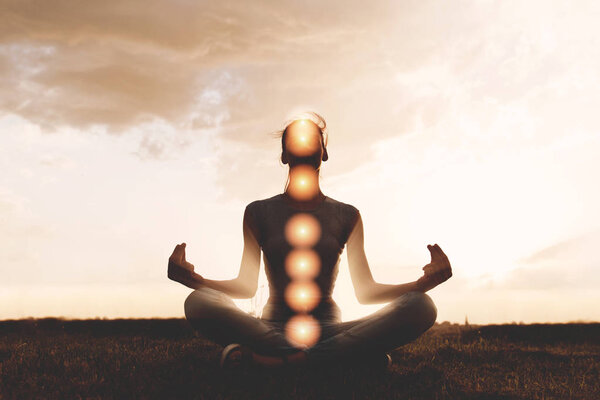 Woman practicing meditation in sunset, with chakras marked