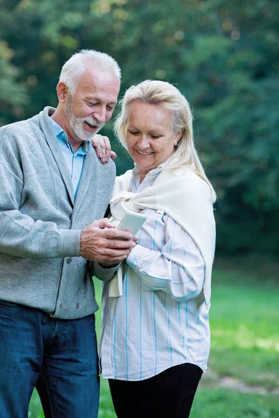 Gelukkige Senior Paar Met Behulp Van Een Telefoon Buitenshuis — Stockfoto
