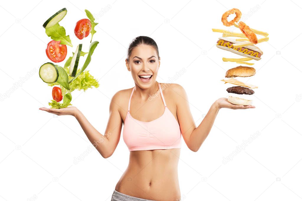Beautiful, fit woman choosing between a healthy and unhealthy food