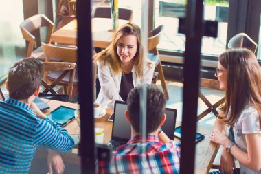 Bir grup genç bir kafede oturuyor, konuşuyor ve eğleniyorlar.