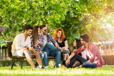 Bir grup genç insan parkta bankta dışarıda eğleniyor