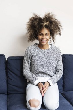 Güzel Afrikalı-Amerikalı kadın kanepe gülümseyen üzerinde oturuyordu