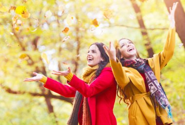 İki güzel genç kadın yaprakları bir parkta atma zevk