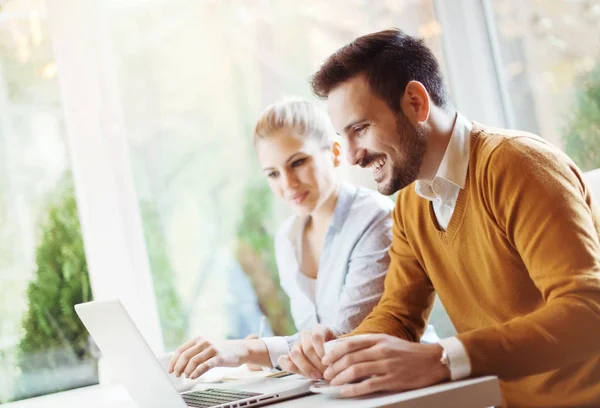 Two people working in the office on laptop