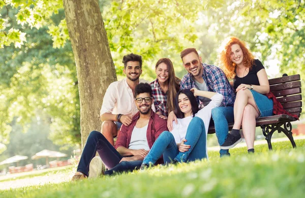 Groep Jongeren Buiten Plezier Bankje Park — Stockfoto