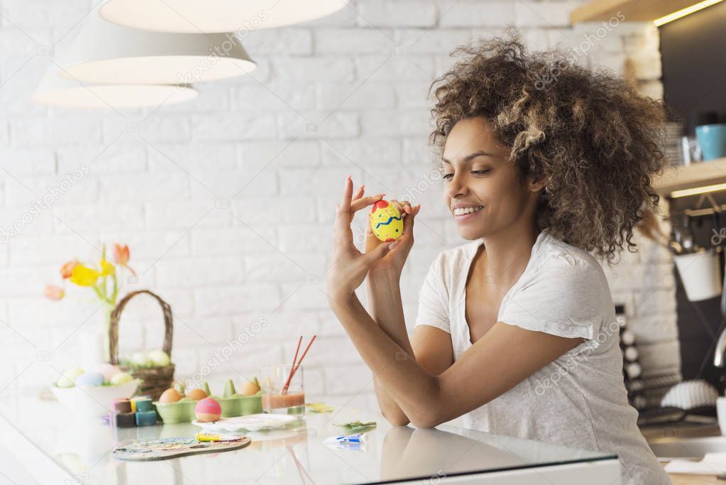 Beautiful African American woman coloring Easter eggs
