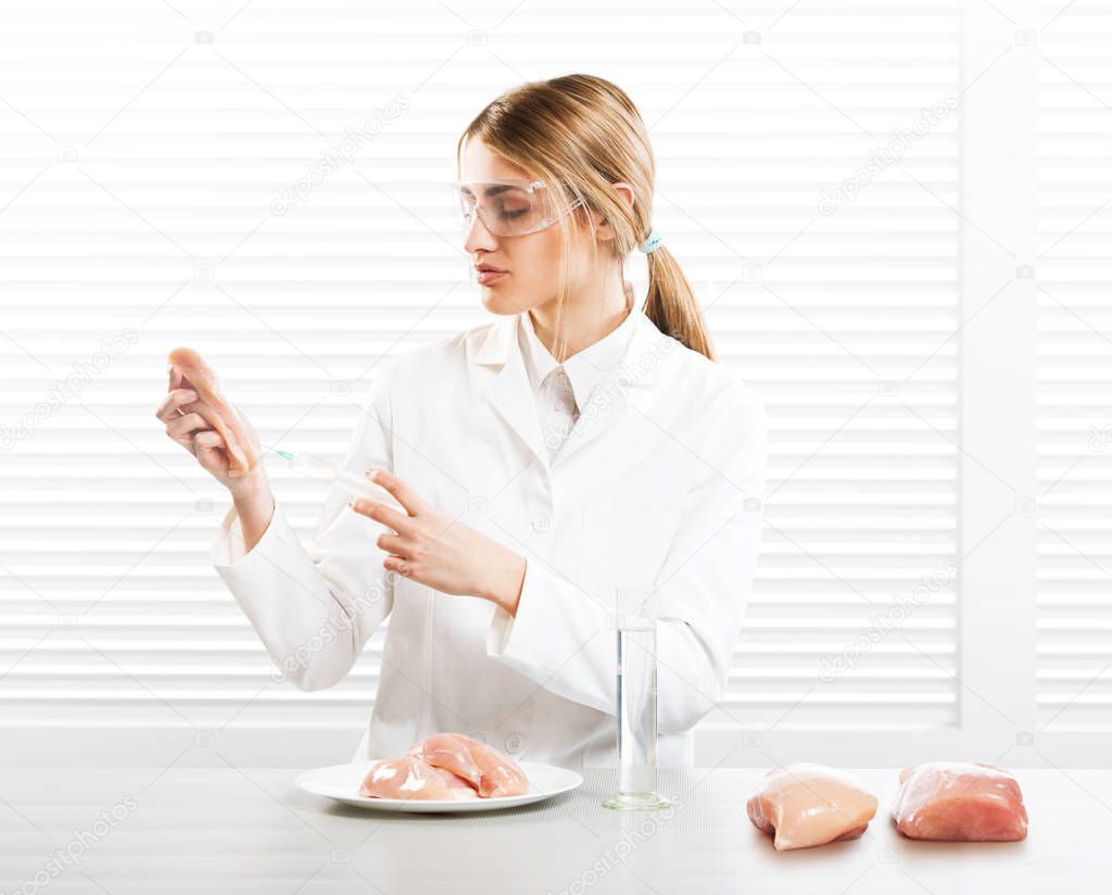 Woman scientist injecting meat with synthetic substances, GM food