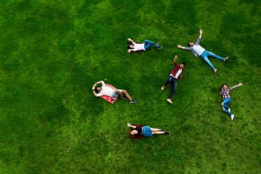 Gençlerin grup gülümseyen mutlu, çimenlerin üzerinde döşeme