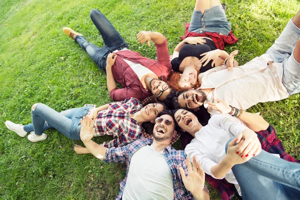 Grupa Młodych Ludzi Leżąc Trawie Koło Szczęśliwy Uśmiechnięty — Zdjęcie stockowe