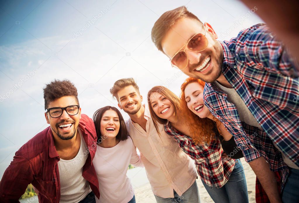Group of young people standing in a circle, outdoors, making a selfie