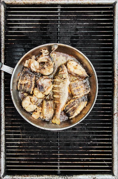 Fish fried in oil, in a pan on stove