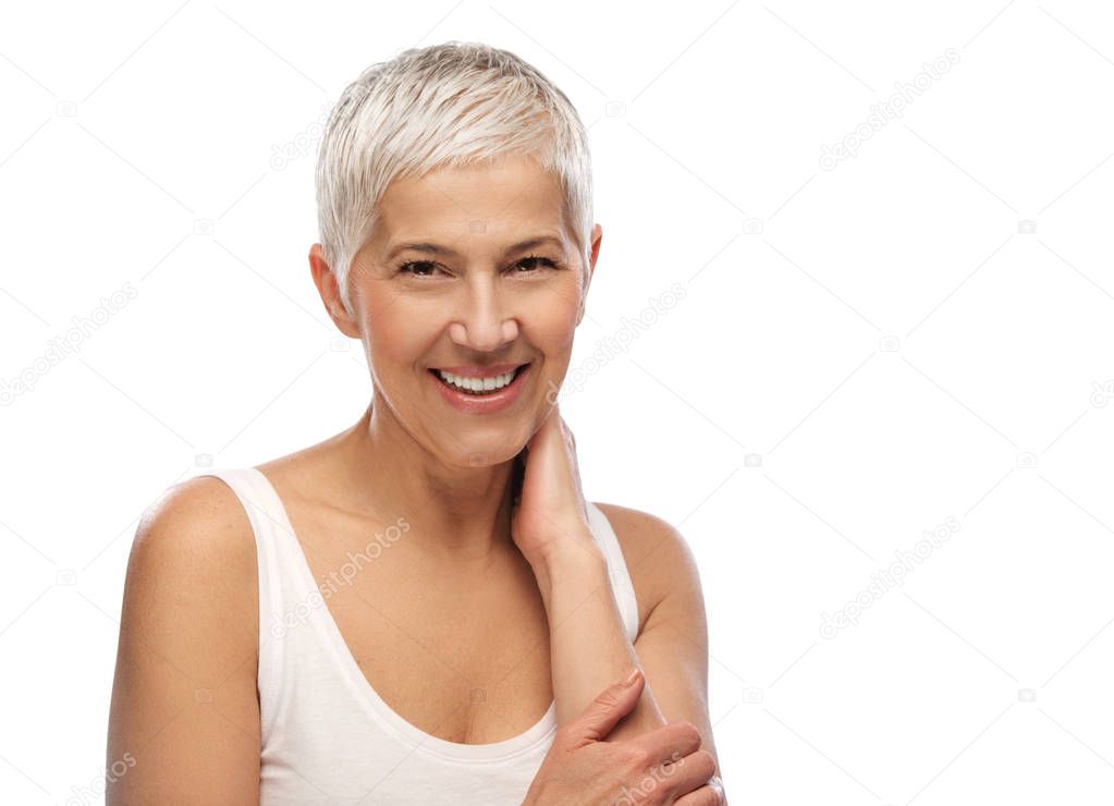 Portrait of a beautiful elderly woman, smiling, hand on neck isolated on white background