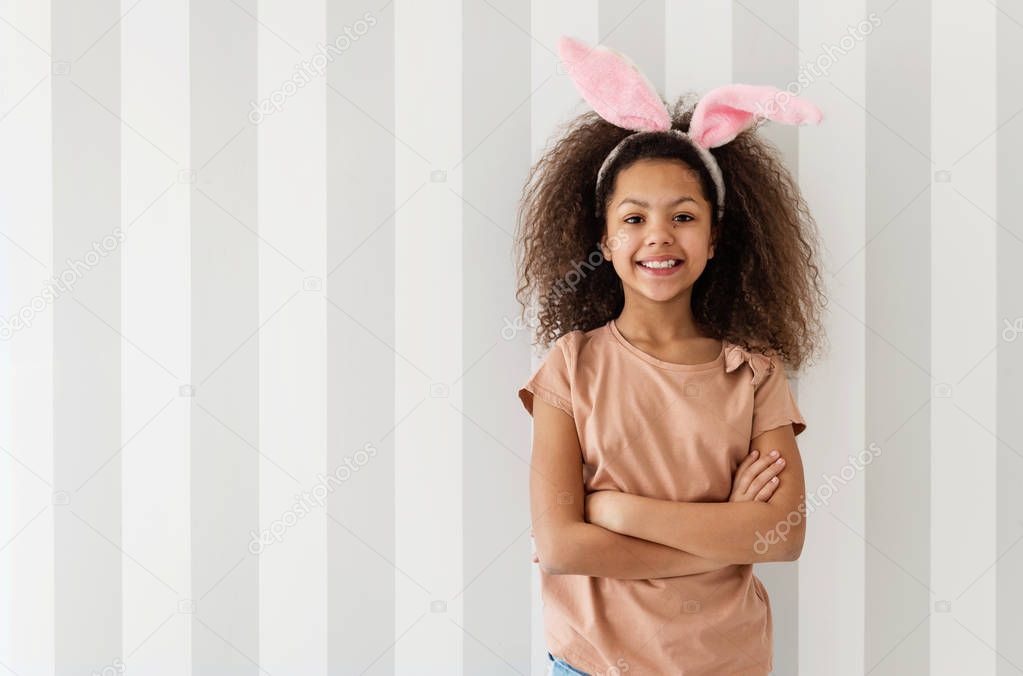 Cute girl smiling over a striped wall with bunny ears