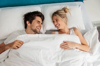 Genç bir çift yatakta uzanıyor, eğleniyor.