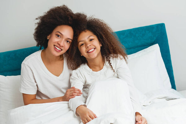 Mother and daughter enjoying on the bed, happy, smiling 