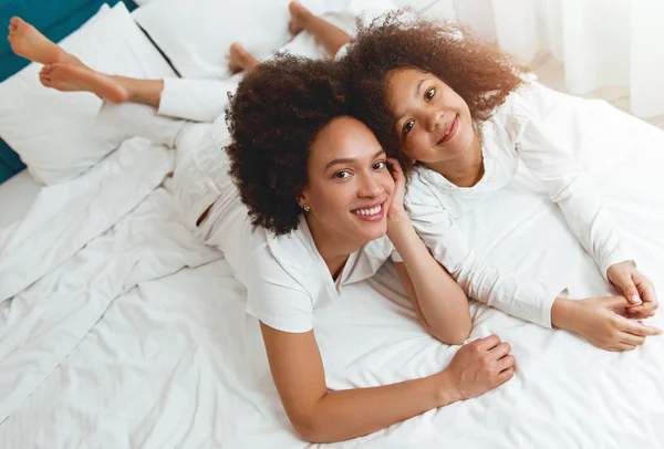 Mother and daughter enjoying on the bed, happy, smiling