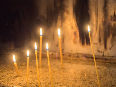 Karanlık bir odada ışıklı birkaç mum.