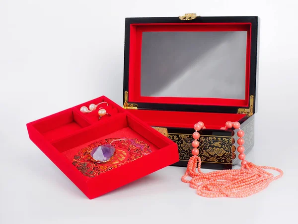 Jewel-box with coral bead necklace on white background.