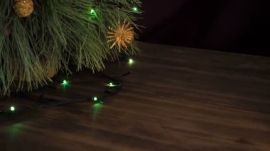Adam kutu hediye Noel ağacının altına koyar. Köknar ahşap masa standı ve parlayan garland ve Noel oyuncaklar ile dekore edilmiş.