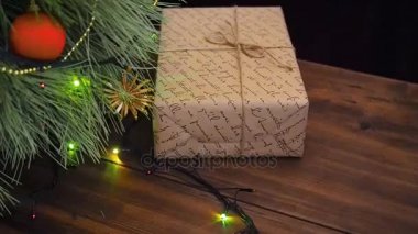 Hediye kutusu altındaki ağacı vardır. Hediye broun gazetede Paketli ve sicim ile bağlı. Köknar ağacı dalları üzerinde Noel çelenk.