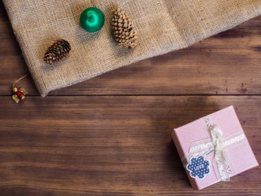 Vintage hediye kutusu, çam kozalakları, Noel oyuncak, şerit yay üzerinde ahşap ve çuval bezi arka plan, fotoğraf üstten görünüm ile. Metin için yer kopyalayın.