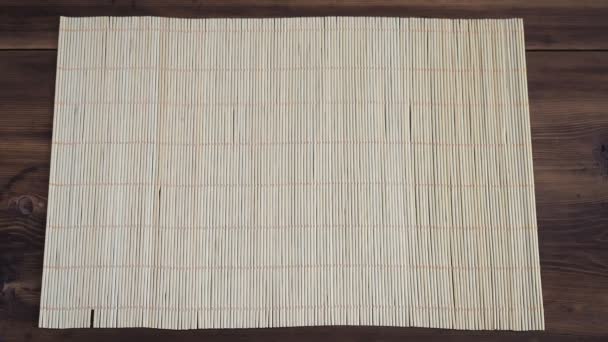 De man zet op houten tafel van de oude planken met servet gemaakt van bamboe witte schotel — Stockvideo