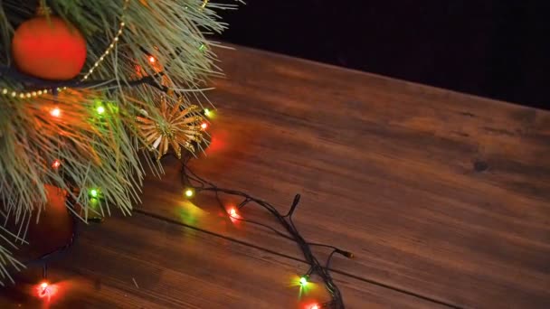 O homem coloca caixas de presente debaixo da árvore de Natal. Fir stand sobre a mesa de madeira e decorado com guirlanda brilhante e brinquedos de Natal . — Vídeo de Stock