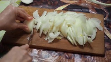 Genç kadın mutfakta soğan ahşap kesme tahtası üzerinde bıçak ile kesme