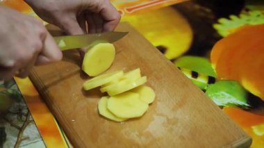 Genç kadın mutfakta patates ahşap kesme tahtası üzerinde bıçak ile kesme