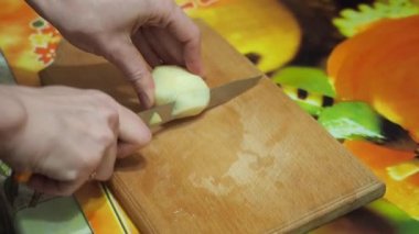 Genç kadın mutfakta patates ahşap kesme tahtası üzerinde bıçak ile kesme