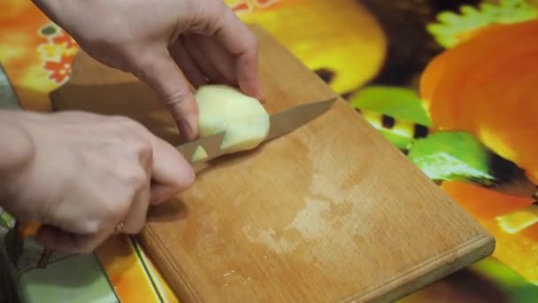 Young woman in the kitchen cutting the potatoes with knife on wooden cutting board — Stock Video