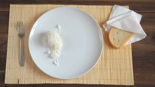 L'uomo mette un cucchiaio di legno su un piatto di ceramica bianca, riso appena fatto al vapore e carne fritta con verdure. — Video Stock