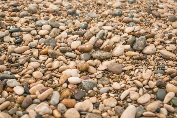 Текстура сухой круглой морской гальки на галечном пляже, крупным планом. Каменный фон. Маленькие камни текстура гравия, фон из цветного круглого камня — стоковое фото