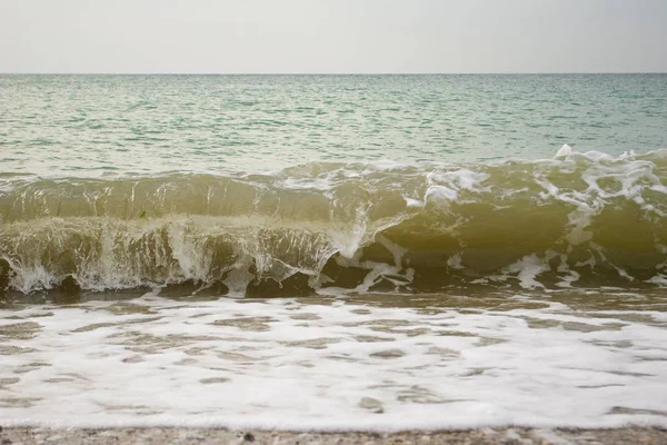 Köpük dalgalar deniz kıyısı üzerinde yakın çekim. Bulutlu gün deniz manzarası — Stok fotoğraf