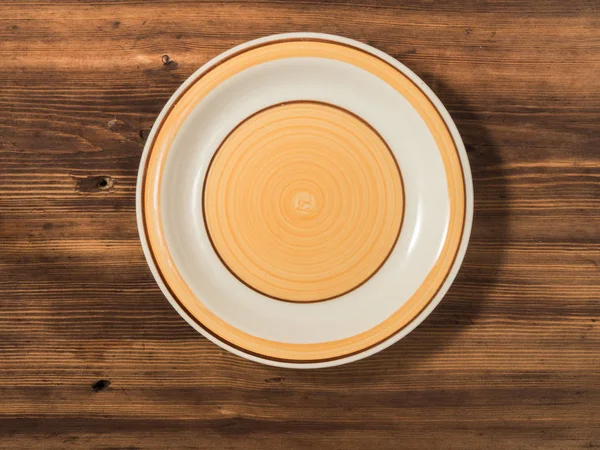 Oranje ronde plaat is gefotografeerd bovenaanzicht op een achtergrond van oude houten tafel planken. — Stockfoto