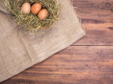 Kırsal çevre kahverengi tavuk yumurtası, çuval bezi ve saman eski ahşap plakalar arka plan üzerine bir parça ile arka plan. Üstten Görünüm. Paskalya kartları için yaratıcı arka plan