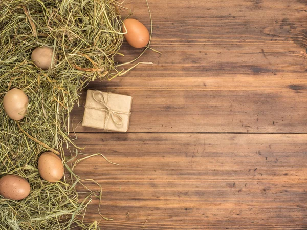 Fondo ecológico rural con huevos de pollo marrón, caja de regalo y paja en el fondo de tablones de madera viejos. La vista desde arriba. Fondo creativo para tarjetas de Pascua — Foto de Stock