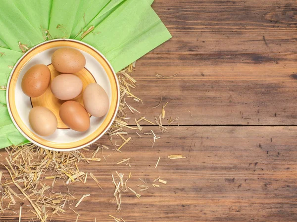 Fondo ecológico rural con huevos de pollo marrón, una pieza de arpillera y paja en el fondo de tablones de madera viejos. La vista desde arriba. Fondo creativo para tarjetas de Pascua — Foto de Stock