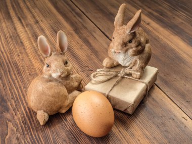 Paskalya tavşanları ahşap hediye kutusu ile eski kurulları tablosundan arka plan üzerinde dize ve kahverengi tavuk yumurtası ile bağlı
