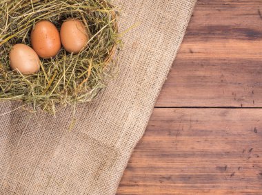 Kırsal çevre kahverengi tavuk yumurtası, çuval bezi ve saman eski ahşap plakalar arka plan üzerine bir parça ile arka plan. Üstten Görünüm. Paskalya kartları için yaratıcı arka plan