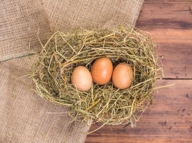 Kırsal çevre kahverengi tavuk yumurtası, çuval bezi ve saman eski ahşap plakalar arka plan üzerine bir parça ile arka plan. Üstten Görünüm. Paskalya kartları için yaratıcı arka plan